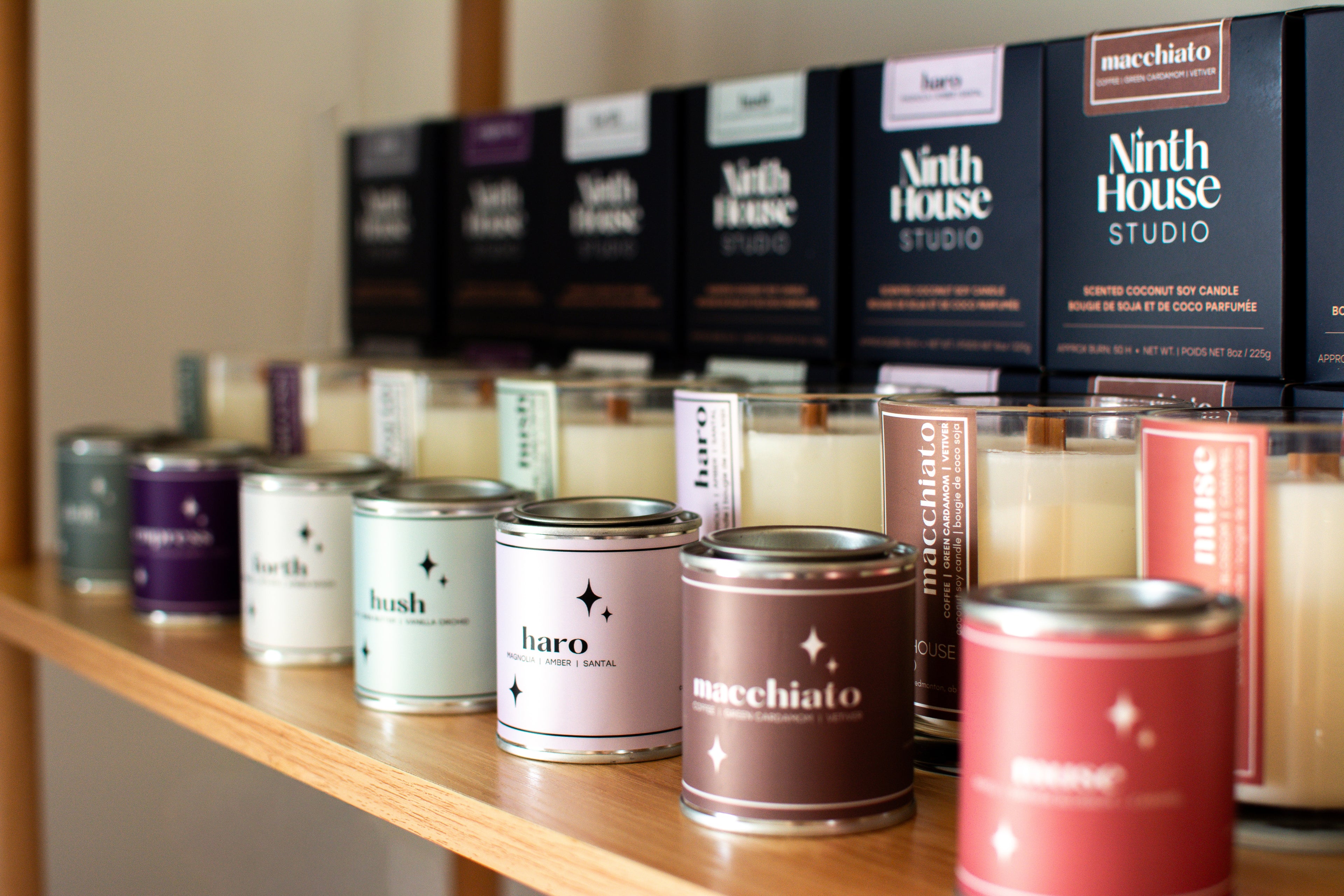 Assorted candles and candle containers on a shelf with 'Ninth House Studio' branding.