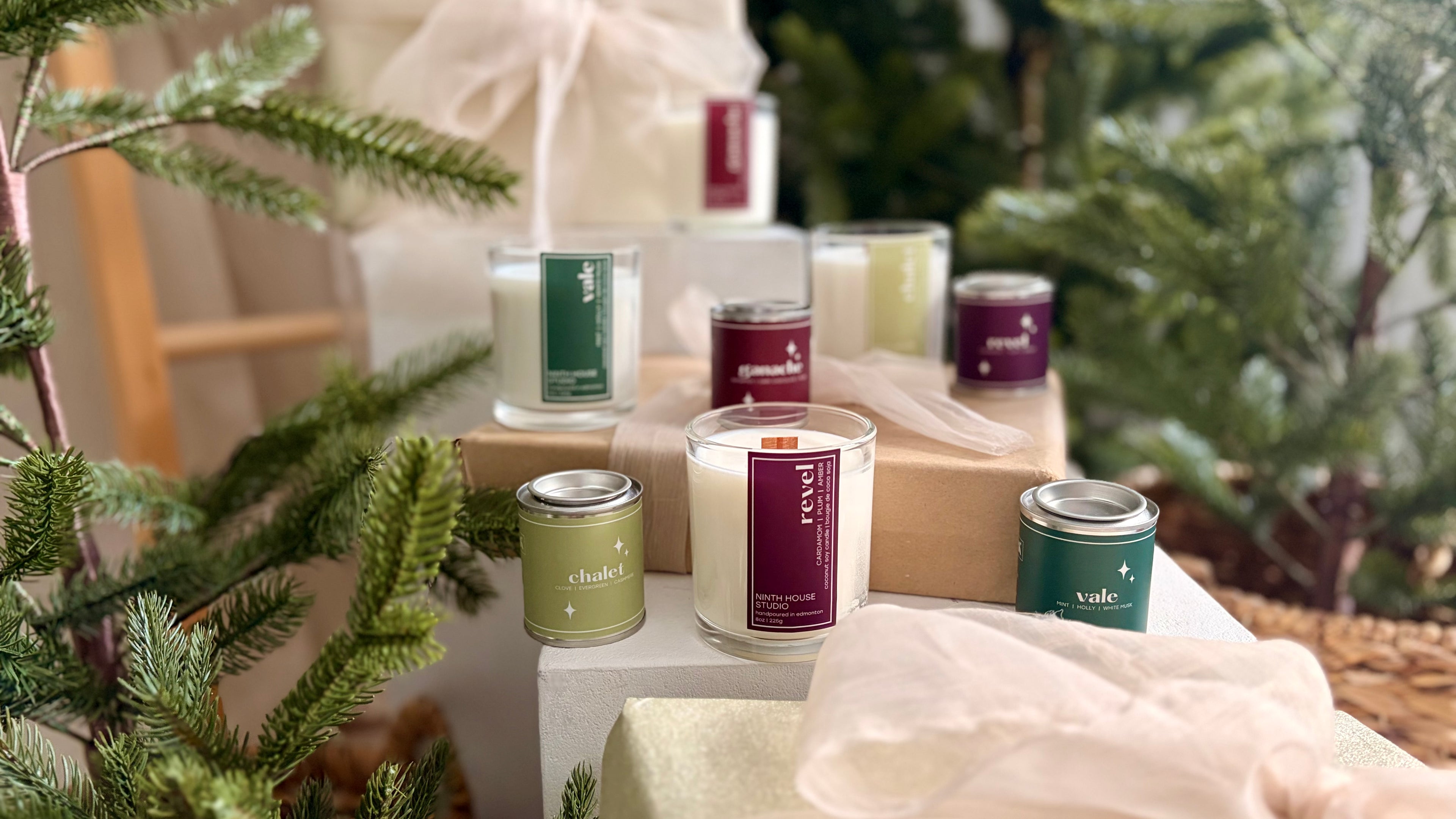 Collection of candles and gift boxes on a table with Christmas decorations.