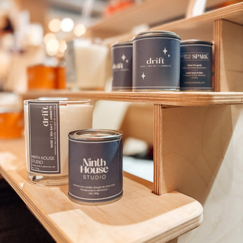 Cans of Ninth House Studio and Drift on a wooden shelf with a blurred background
